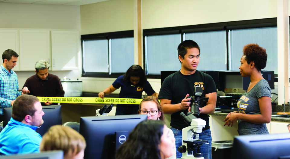 students with crime scene tape in lab