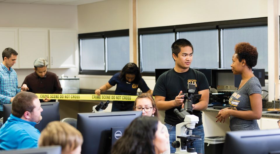 students with crime scene tape in lab